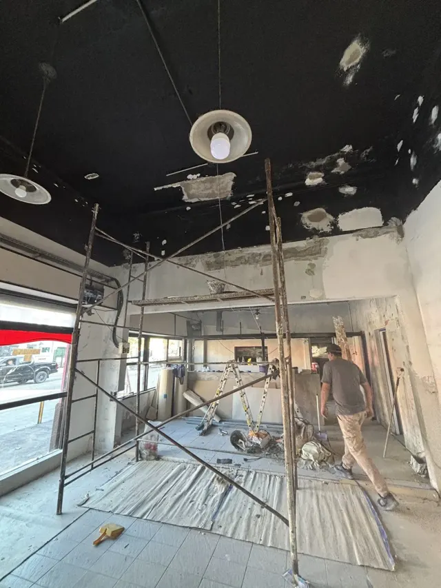 Local comercial en obra, con andamio y luminarias colgantes del cielorraso
